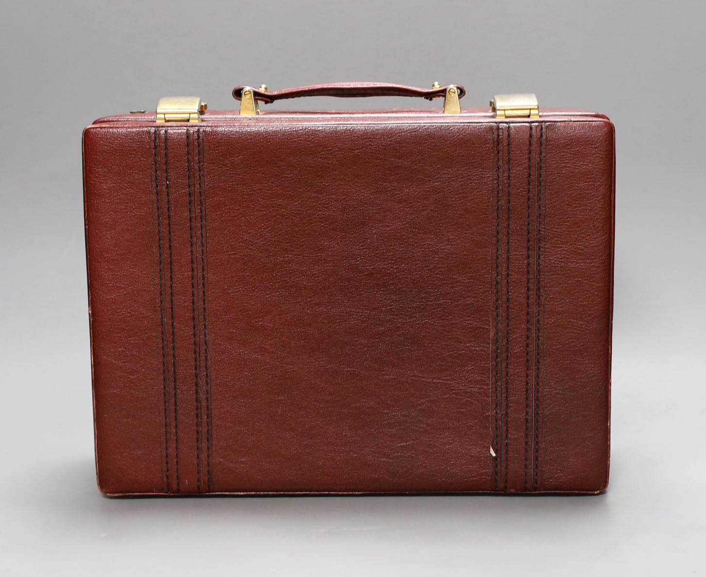 A small red leather mounted suitcase